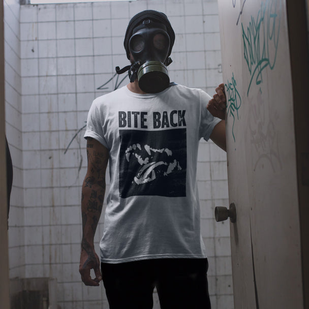 Person wearing a gas mask and 'Bite Back' t-shirt in a graffiti-covered bathroom.