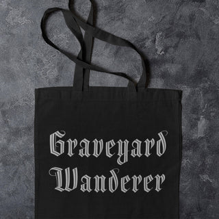 Black tote bag with 'Graveyard Wanderer' text on a textured gray background
