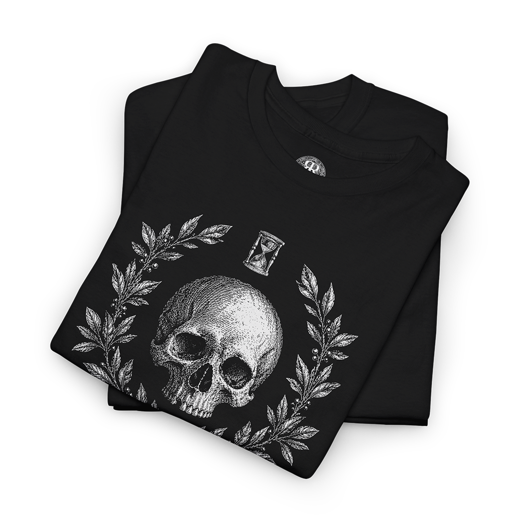 A folded black t-shirt with a detailed white graphic print of a skull, laurel wreath, and an hourglass on the front, displayed on a clean white background.