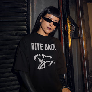 Person wearing a black t-shirt with 'BITE BACK' text and graphic, standing against a dark background.