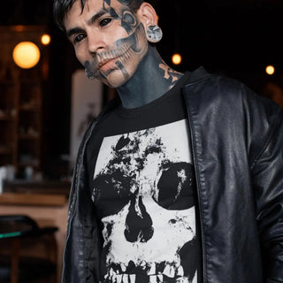 Person wearing a black leather jacket and a black t-shirt with a white skull design in an indoor setting.