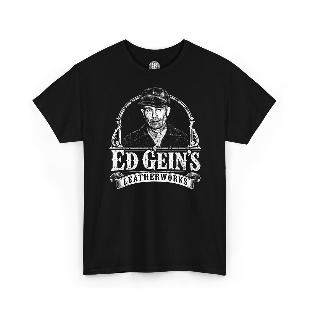 A black short-sleeve crewneck t-shirt featuring a distressed white graphic print of Ed Gein's portrait and the text 'ED GEIN'S LEATHERWORKS' on the front, displayed against a solid white background.