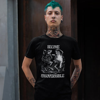 A tattooed man with bright green hair wears a black graphic t-shirt featuring a white print of a frog and the text 'BECOME UNGOVERNABLE'.
