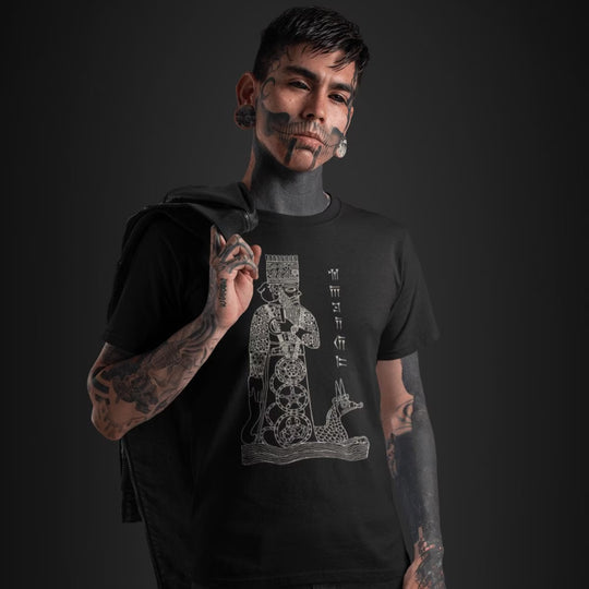 Tattooed man wearing a blackGod Marduk T-Shirt with a graphic design on a dark background