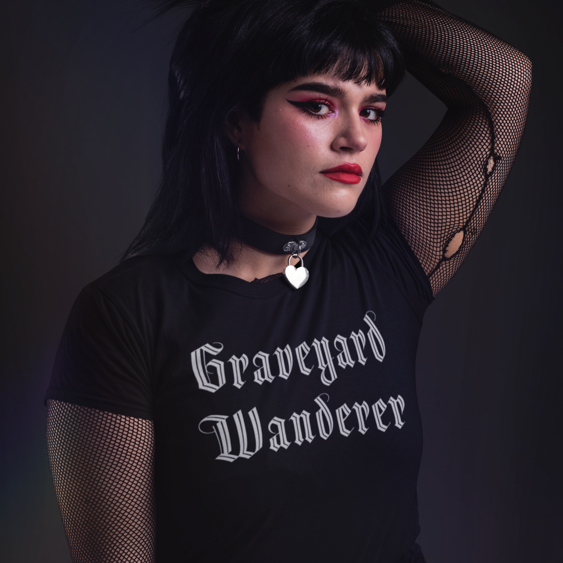 Woman wearing a black t-shirt with 'Graveyard Wanderer' text against a dark background