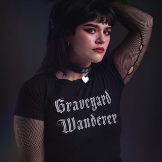 Woman wearing a black t-shirt with 'Graveyard Wanderer' text against a dark background