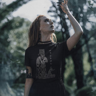 Woman wearing a black God Marduk T-Shirt, standing in a forest.