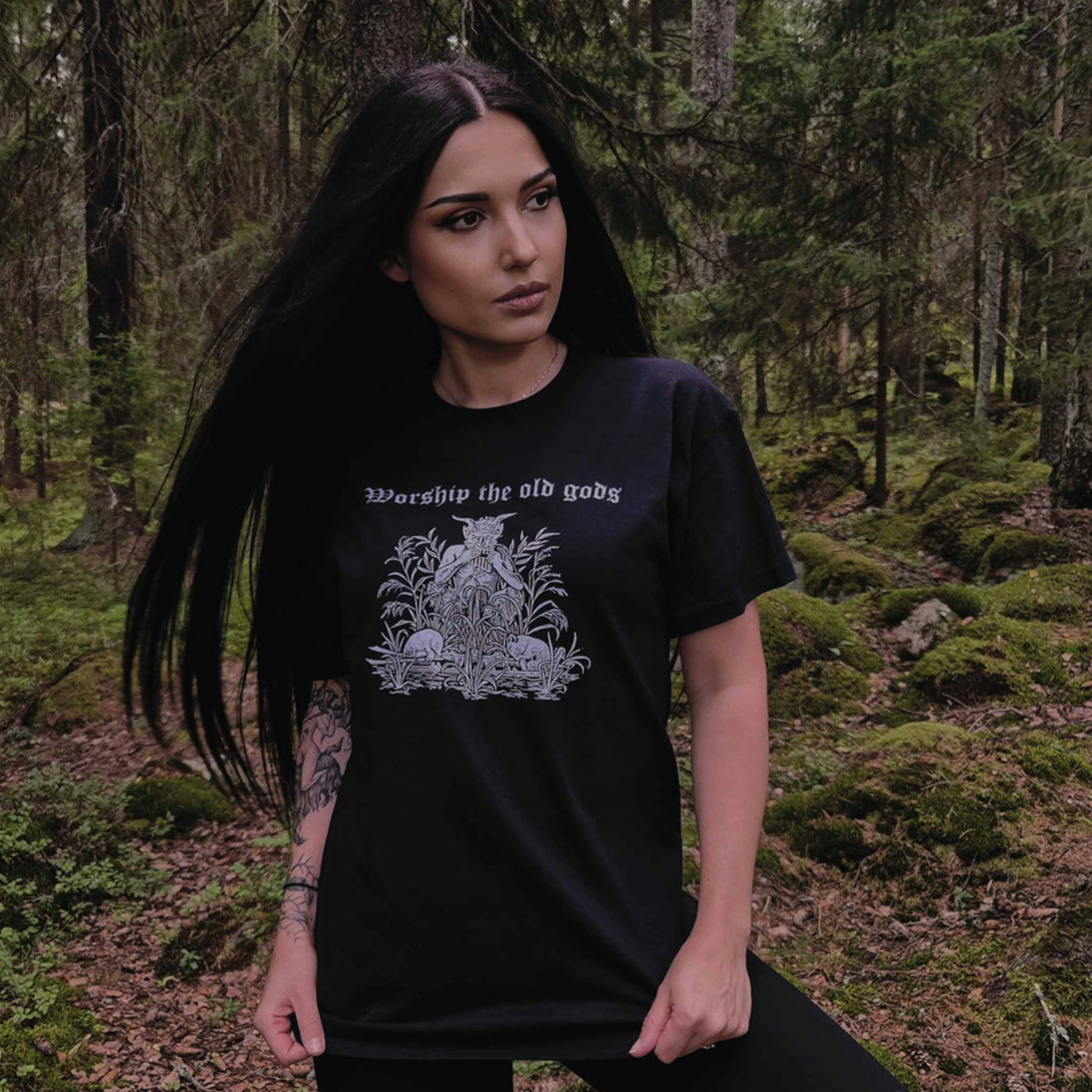 Woman wearing black Worship the Old Gods T-Shirt in a forest setting