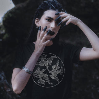 Person wearing a black t-shirt with a bird design, posing with hands on face.