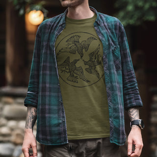 Person wearing a green t-shirt with a bird design and a plaid shirt over it, standing outdoors.