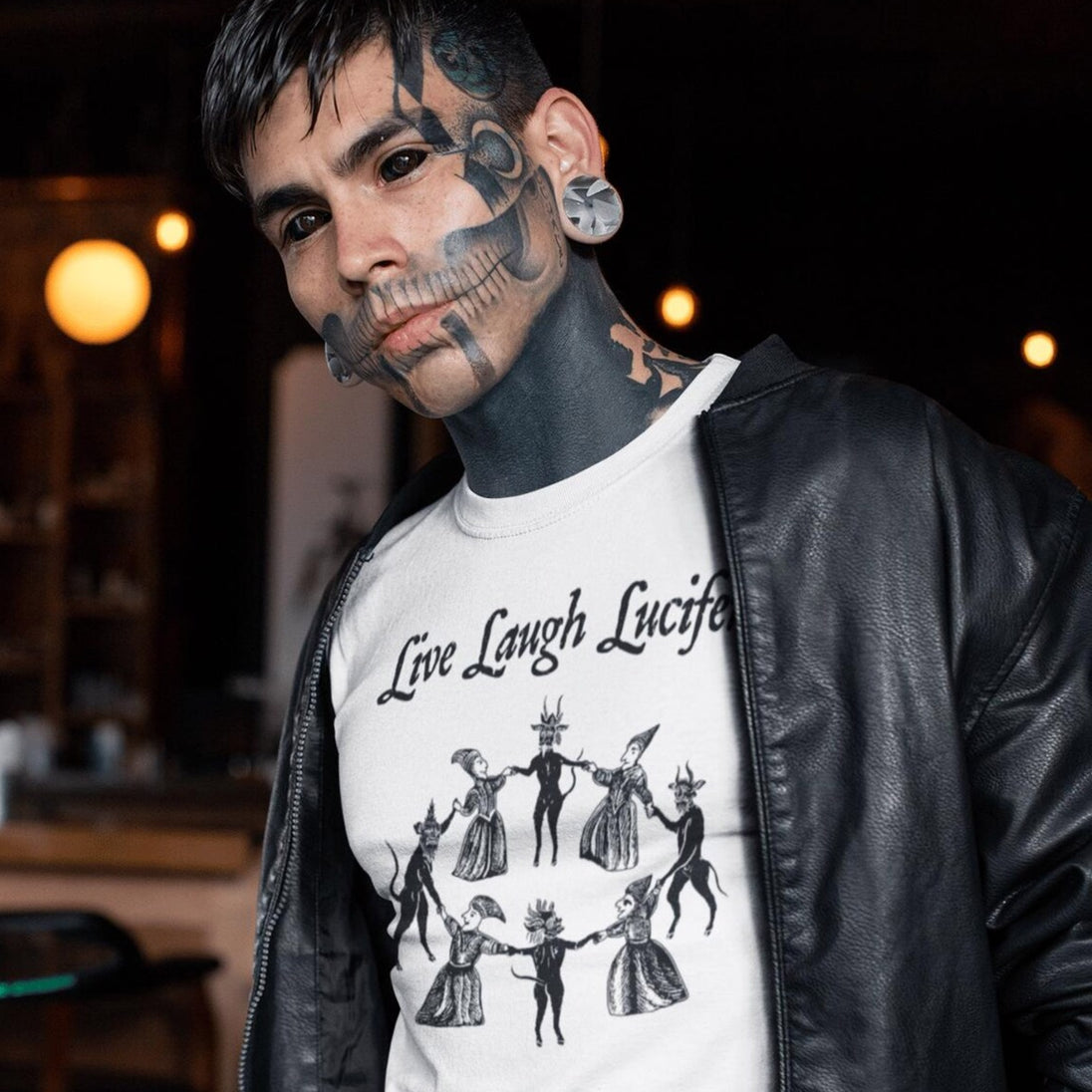 Tattooed man wearing white Live Laugh Lucifer t-shirt