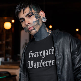 Man wearing a black leather jacket and 'Graveyard Wanderer' t-shirt with tattoos on face and neck.