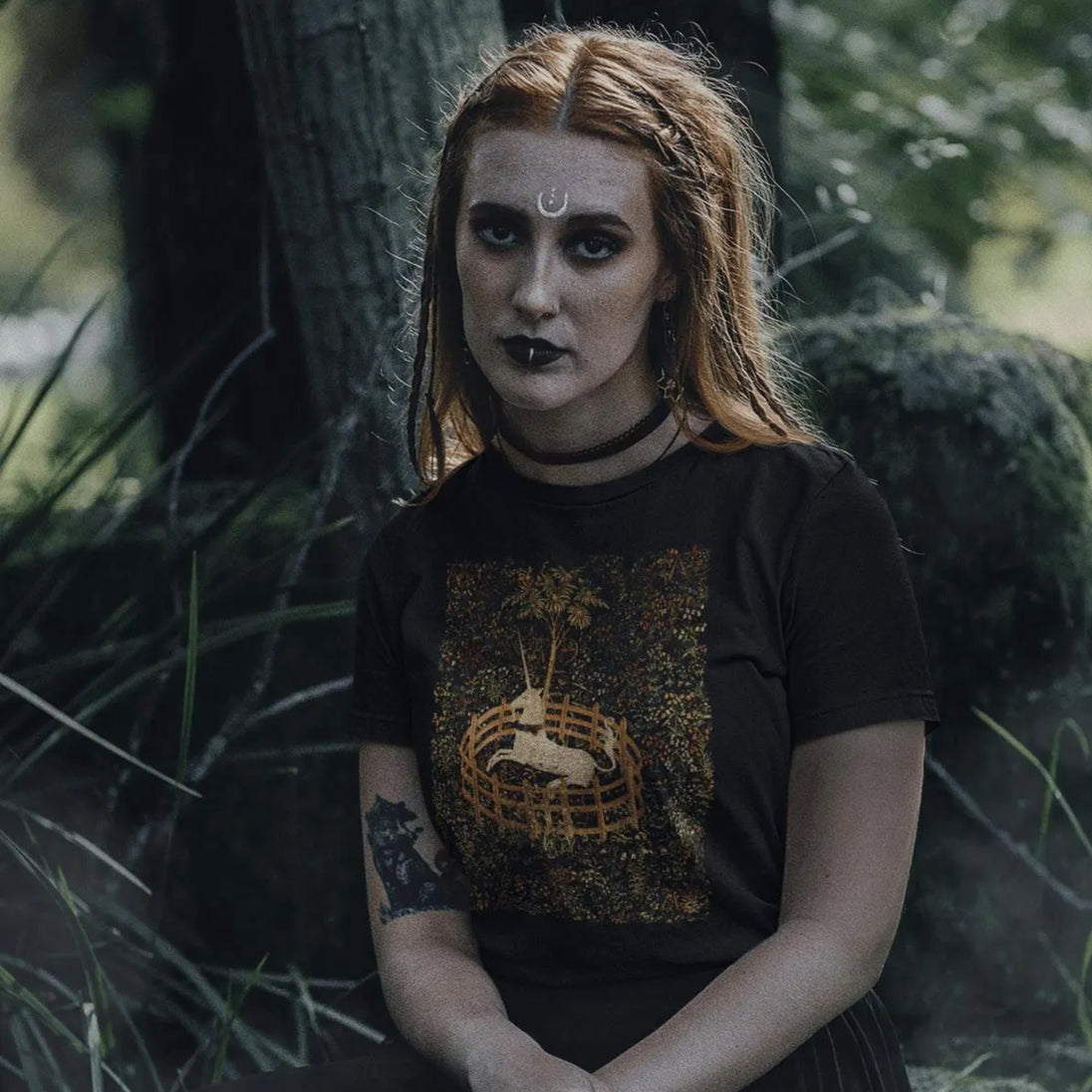 Woman wearing a black t-shirt with a graphic design showing unicorn in captivity