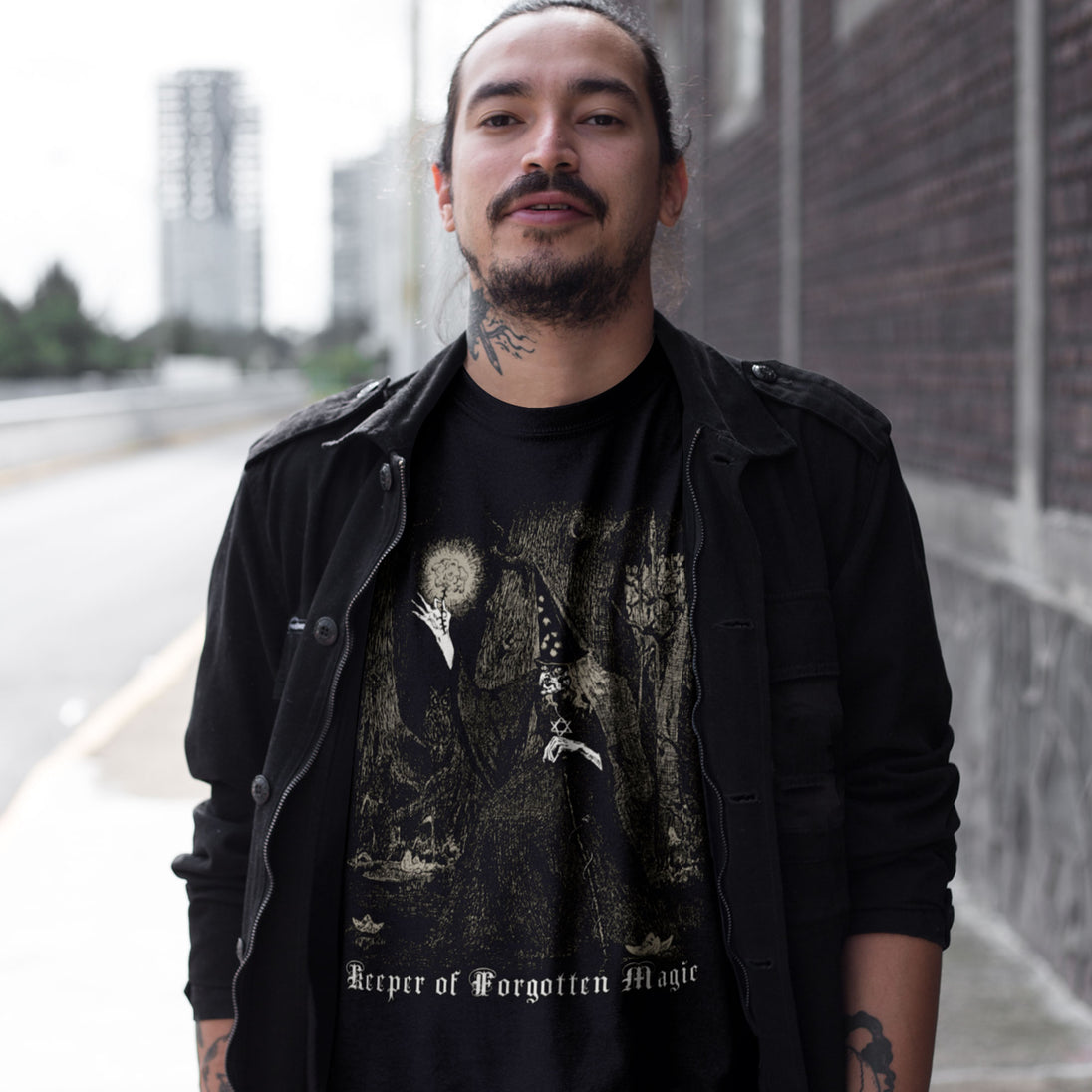 Man wearing a black t-shirt with a graphic design and text 'Keeper of Forgotten Magic'.