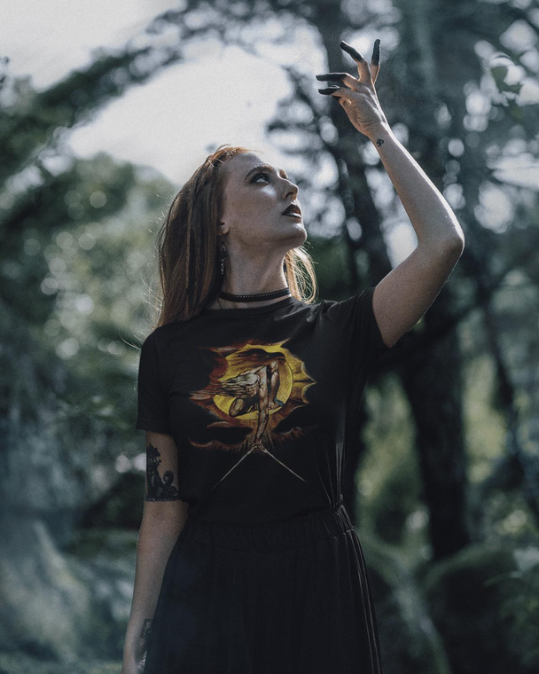 Woman wearing a black The Ancient Of Days T-Shirt, standing in a forest.