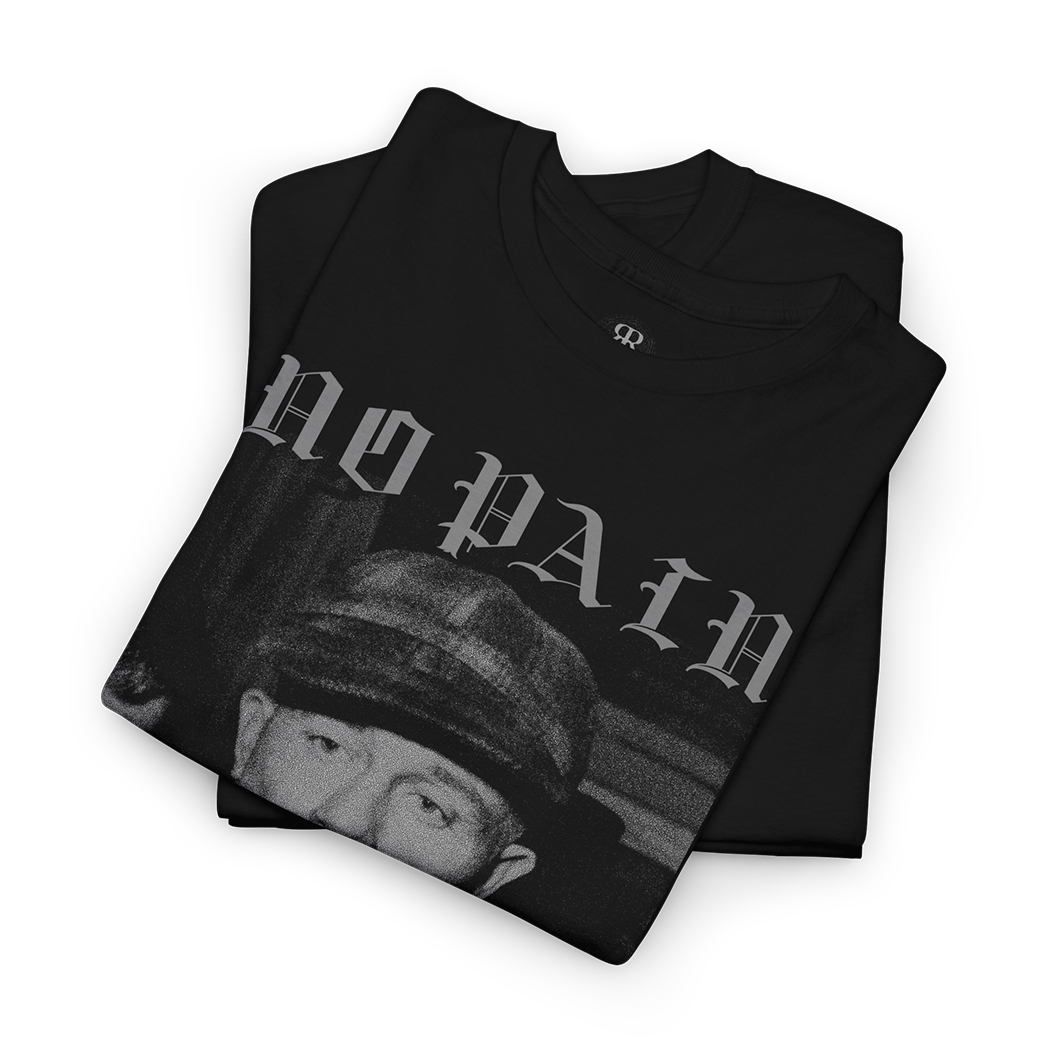 A folded black t-shirt with a grayscale graphic print featuring the text 'NO PAIN' and a face wearing a cap, displayed on a clean white background.