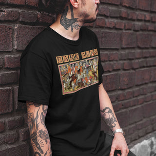Person wearing a black t-shirt with a colorful graphic design against a brick wall.