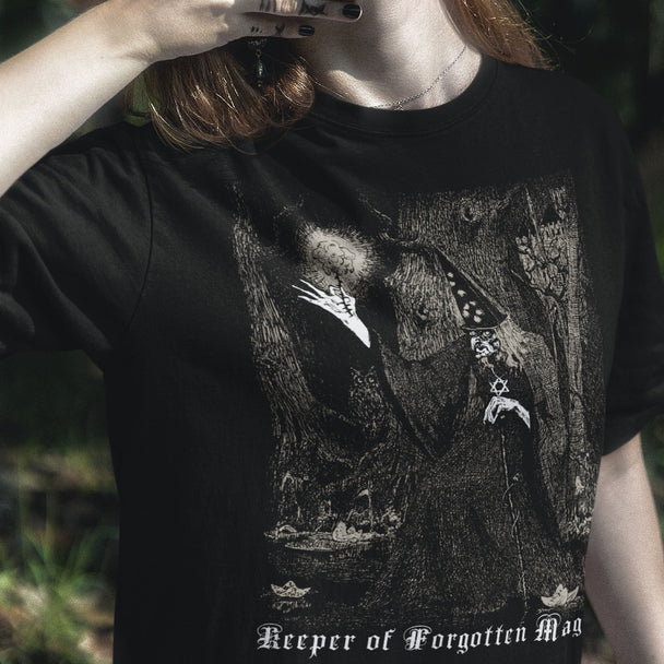 Person wearing a black t-shirt with a graphic design and text 'Keeper of Forgotten Magic'.