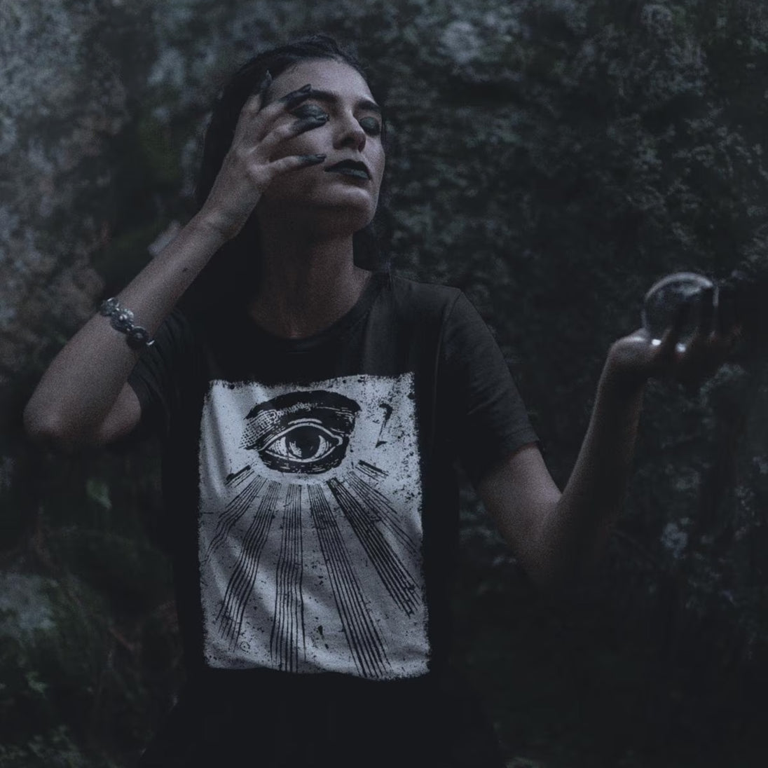 Person wearing All Seeing Eye T-Shirt in a dark, forest-like setting