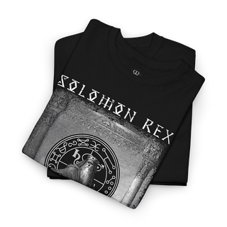 A folded black t-shirt with a grayscale graphic print featuring the text 'SOLOMON REX' and a circular mystical emblem, displayed on a clean white background.