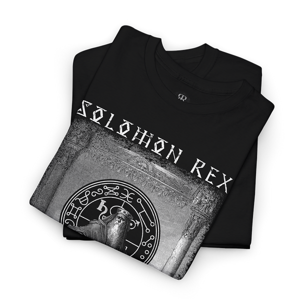 A folded black t-shirt with a grayscale graphic print featuring the text 'SOLOMON REX' and a circular mystical emblem, displayed on a clean white background.