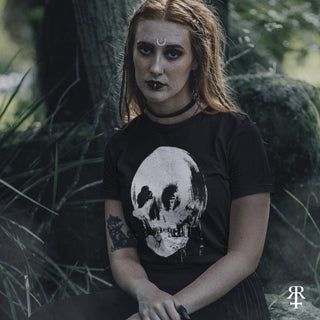 Person wearing a black t-shirt with a skull design in a forest setting
