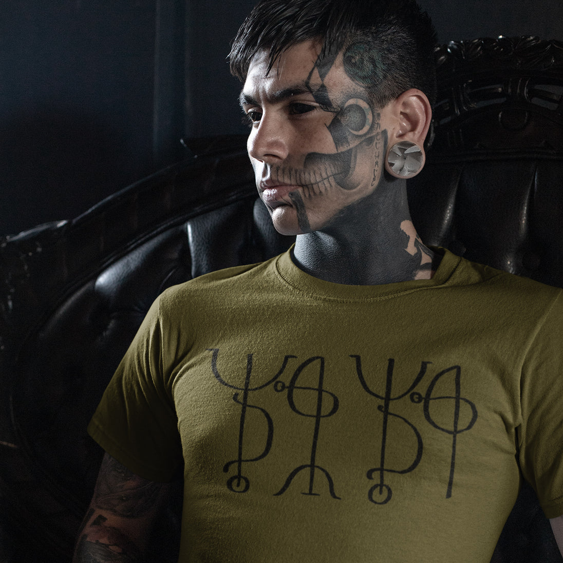 Tattooed man wearing olive green Draumstafir T-Shirt in black print